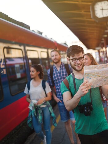 Ladies on tour | © Shutterstock / 501760414
 Personen mit einer Karte vor einem Zug | © Shutterstock / 501760414