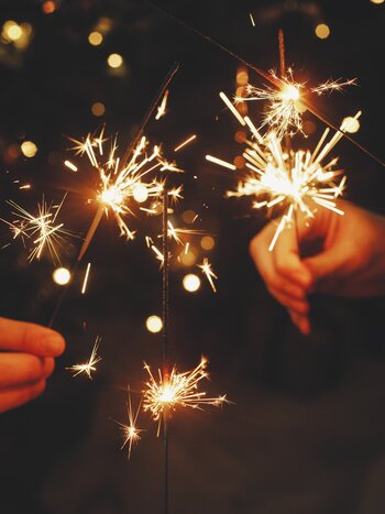 Silvesterreisen mit railtour | © shutterstock / 2216852407 Mehrere Hände halten Wunderkerzen im Dunkeln | © shutterstock / 2216852407
