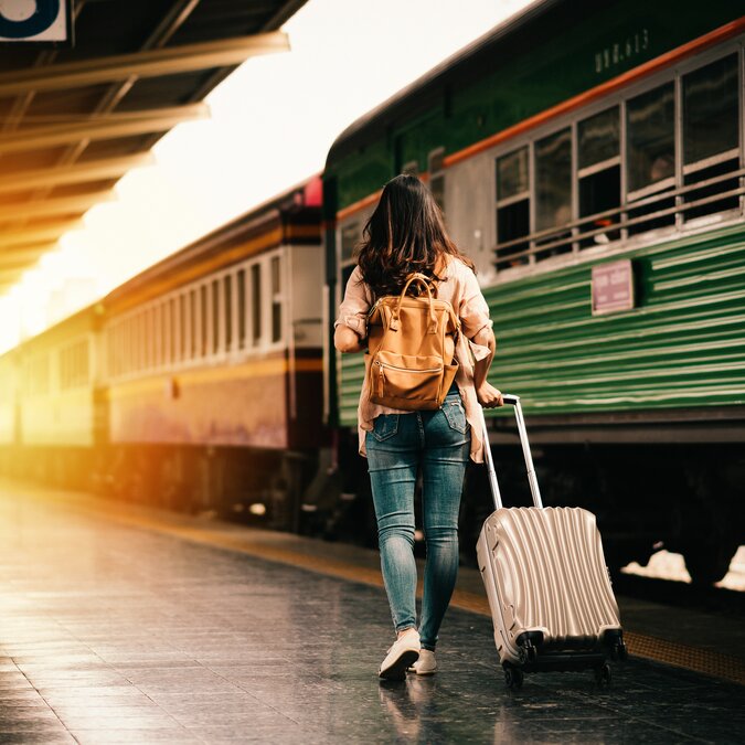 Frau mit Koffer Frau mit Koffer auf Bahngleis vor grünem Zug