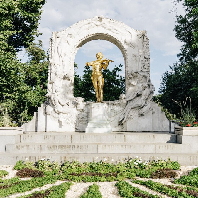 Johann Strauss Denkmal im Stadtpark | © Wien Tourismus | Gregor Hofbauer Die goldene Statue von Johann Strauss II steht im Wiener Stadtpark unter einem kunstvoll verzierten weißen Marmor-Bogen. | © Wien Tourismus | Gregor Hofbauer