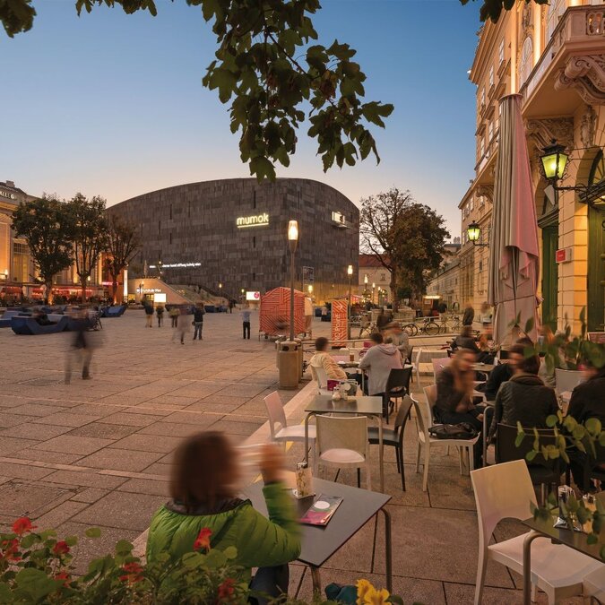Museumsquartier  | © Wien Tourismus | Christian Stemper Blick auf einen Platz in der Abenddämmerung aus einem Café im Hintergrund das mumok und die Halle aus dem Museumsquartier in Wien.  | © Wien Tourismus | Christian Stemper