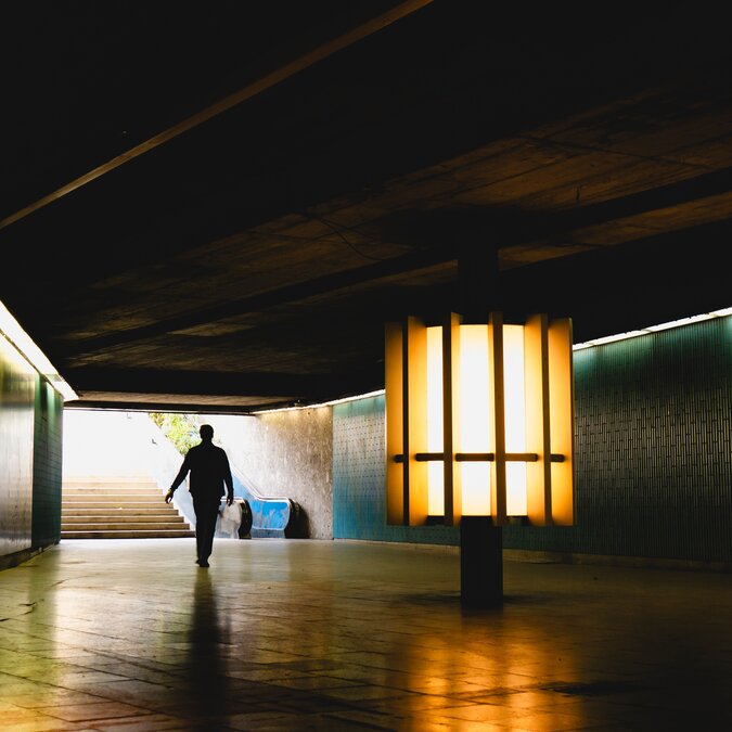 Stadt des Lichts | © Shutterstock 2481850717 Eine Personen-Silhouette wird in eine städtische Unterführung gegossen, beleuchtet von Ambient City Lights, München, Deutschland | © Shutterstock 2481850717