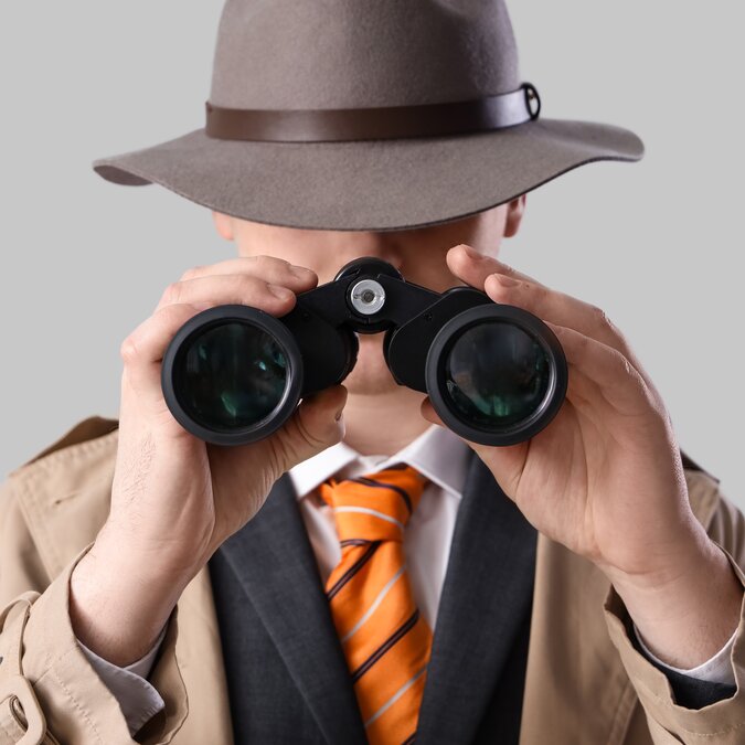 Spionage | © Shutterstock 2448197951 Männlicher Spion, der durch ein Fernglas auf hellem Hintergrund schaut | © Shutterstock 2448197951
