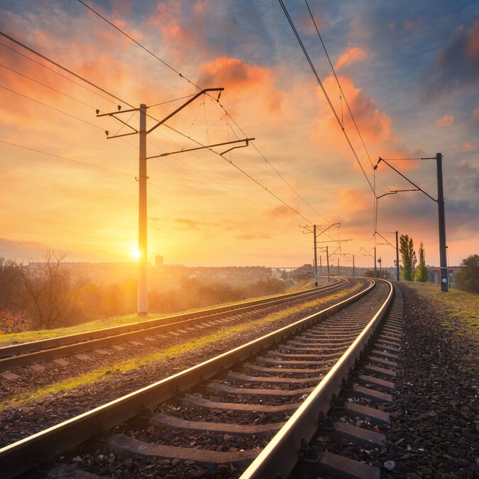 Schmalspurbahn | © Shuterstock 513158971 Bahnhof gegen schönen Himmel bei Sonnenuntergang. Industrielle Landschaft mit Eisenbahn, bunter blauer Himmel mit roten Wolken, Sonne, Bäumen und grünem Gras. | © Shuterstock 513158971