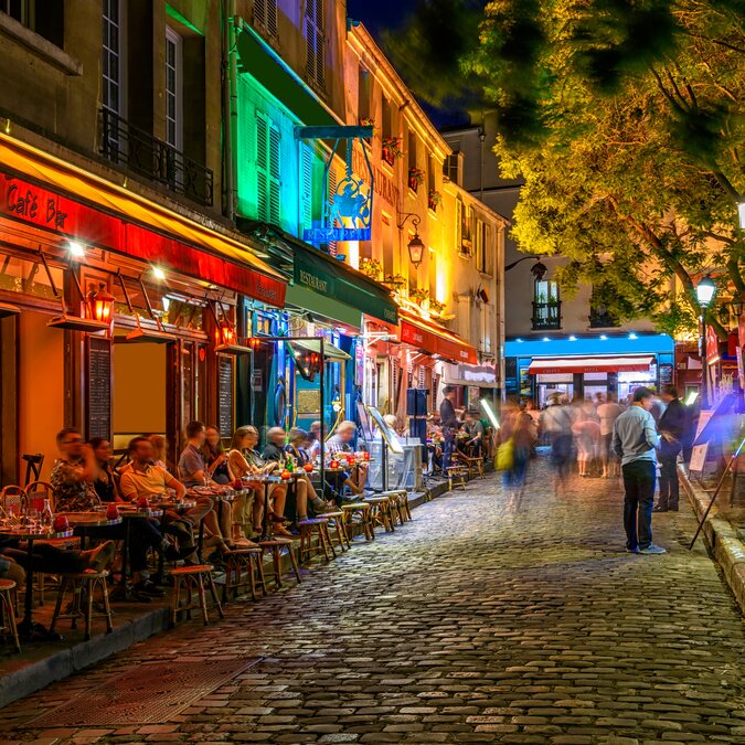 Brasserie in Paris | © Shutterstock 2043692486 Typischer nächtlicher Ausblick auf die gemütliche Strasse mit Tischen für Cafés und Strassenkünstler im Viertel Montmartre in Paris, Frankreich | © Shutterstock 2043692486