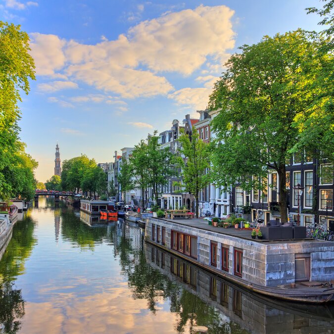 Zu Hause au dem Hausboot | © Shutterstock 608658164 Hausboote am UNESCO Welterbe Prinsengracht Kanal mit der Westerkerk (Westkirche) an einem Sommermorgen mit blauem Himmel und Wolken und Spiegelreflexion in Amsterdam, Niederlande | © Shutterstock 608658164
