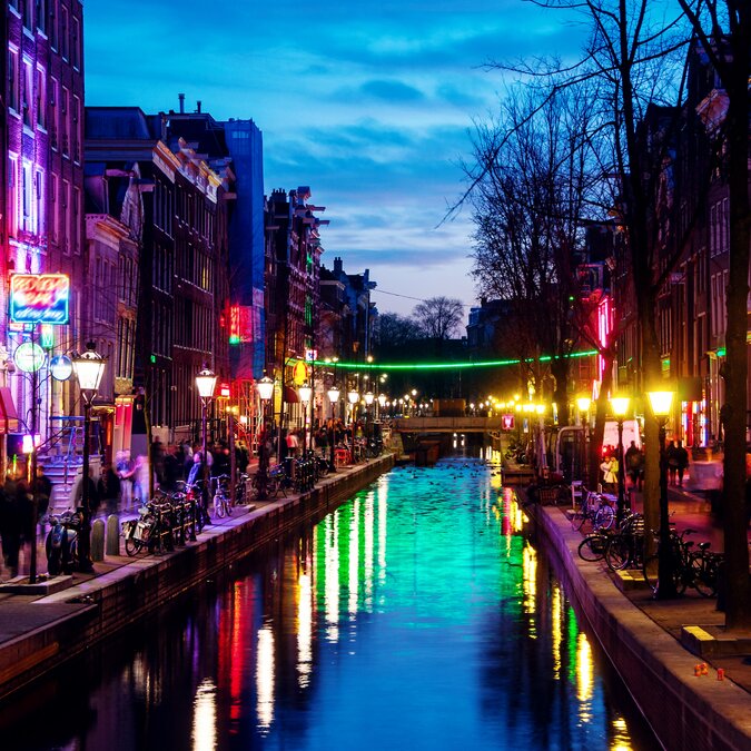 Coffeeshop | © Shutterstock 1419933056 Amsterdam, Niederlande. Nachtblick auf Rot - Leuchtturm in Amsterdam, Niederlande mit Shops, Strip-Clubs, Erwachsenen-Theatern, etc. Sonnenuntergang mit Reflexion im Wasser | © Shutterstock 1419933056