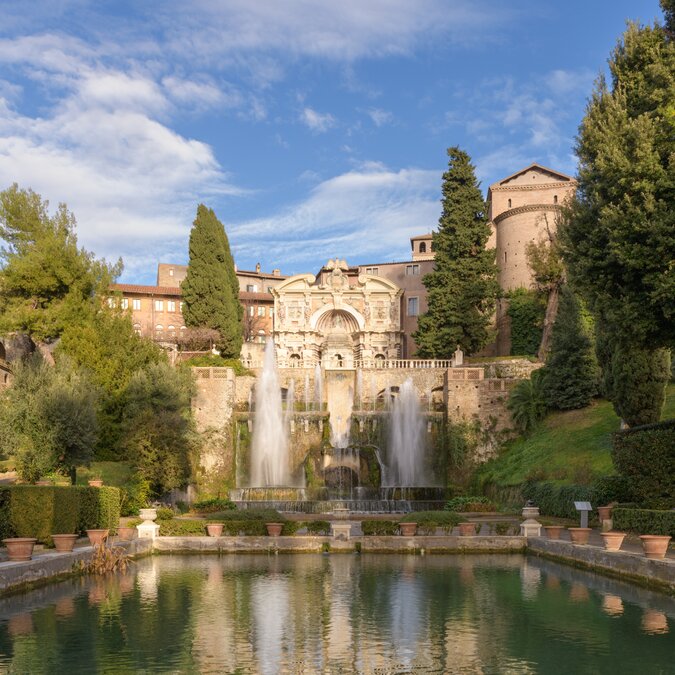 Villa d’Este – von Grotten und Wasserspielen | © Shutterstock 2484725185 Villa d'Este, Tivoli, Italien. Der Neptunbrunnen und der Orgelbrunnen mit seinem Castellum aqua, oder Wasserburg über die Fischteiche | © Shutterstock 2484725185