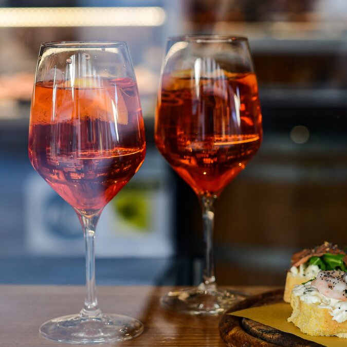 Harry`s Bar | © Shutterstock 1642351627 Italienischer Aperitif Aperol Spritz mit Orangenscheibe in großen runden Gläsern auf einem Holztisch in einer Bar in Italien. Blick durch das Barfenster in Florenz Roma Mailand Venedig Italien. selektiver Fokus | © Shutterstock 1642351627